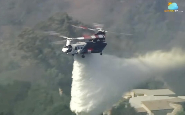 A helitanker drops water on the Palos Fire in La Habra Heights Monday